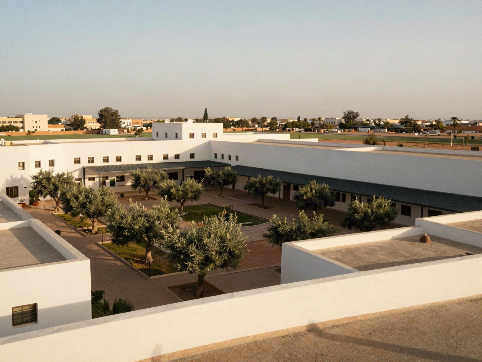 A campus seen from a terrace at the end of the day, several buildings around a planted courtyard.